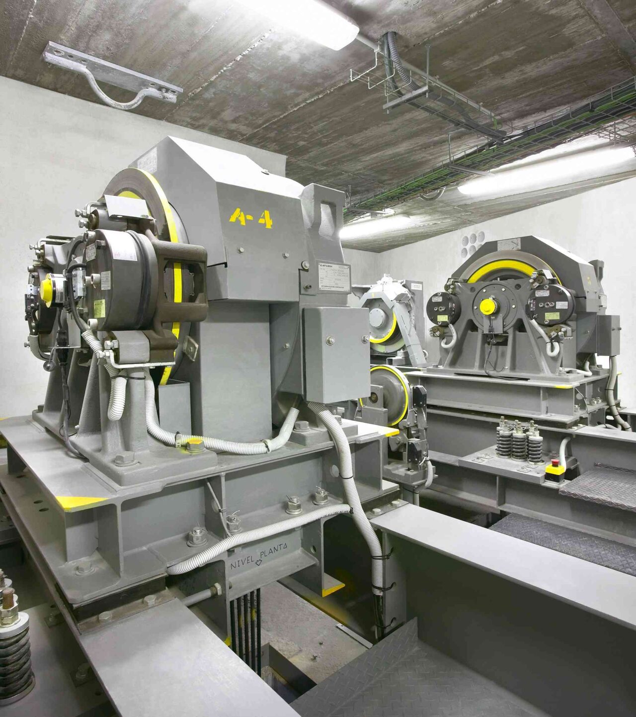 Elevator machinery room with large industrial machines, motors, and cables.