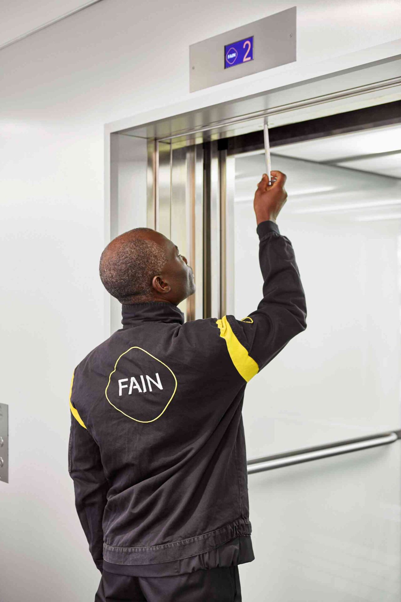 Person performing maintenance on an elevator door.