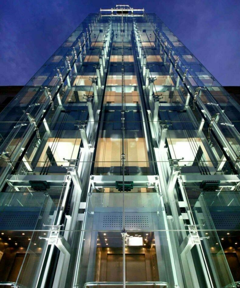 Glass elevator shaft with visible mechanisms and sleek design.
