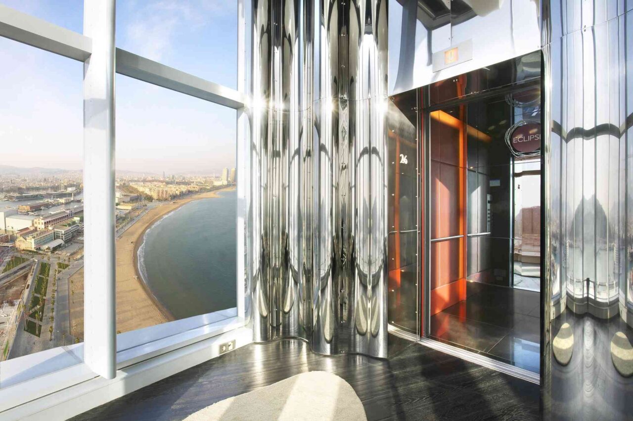 High-rise building interior with panoramic coastal city views, showcasing the beach, sea, and skyline.